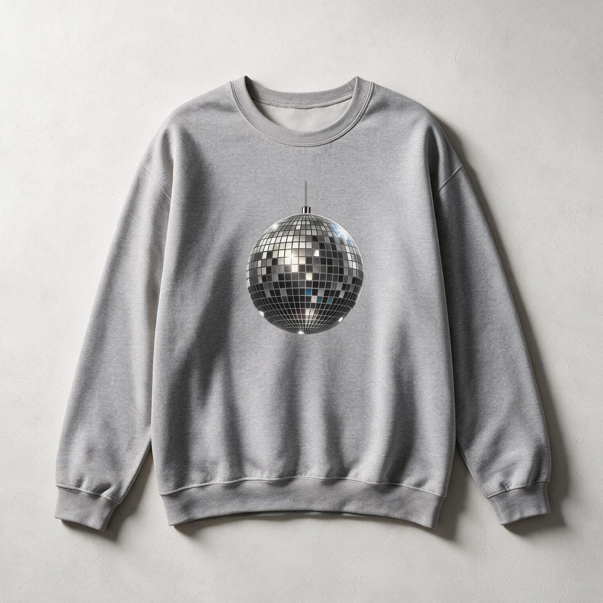 A light gray crewneck sweatshirt featuring a large graphic of a silver disco ball on the chest, laid flat against a neutral light gray background.