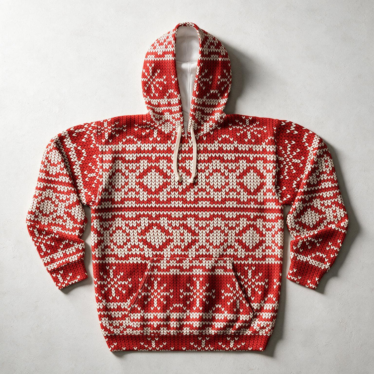 A red and cream knit pullover hoodie with a Nordic/Fair Isle pattern, laid flat on a light gray textured background.