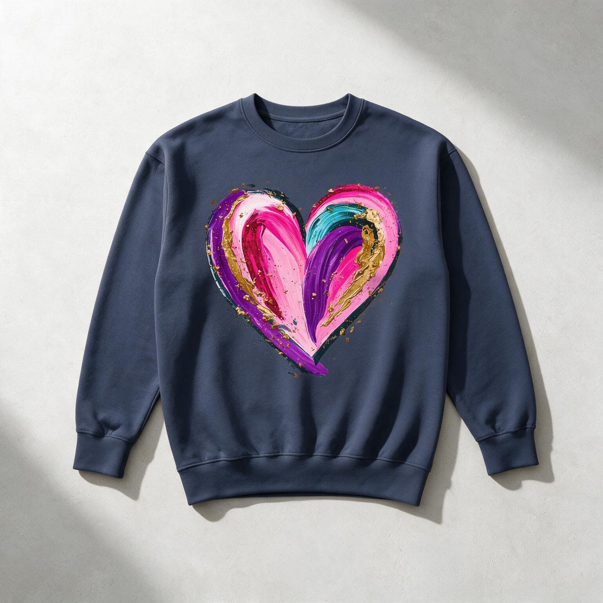 A navy blue crewneck sweatshirt with a large, colorful abstract heart graphic on the chest, displayed flat against a light gray textured background with soft shadows.