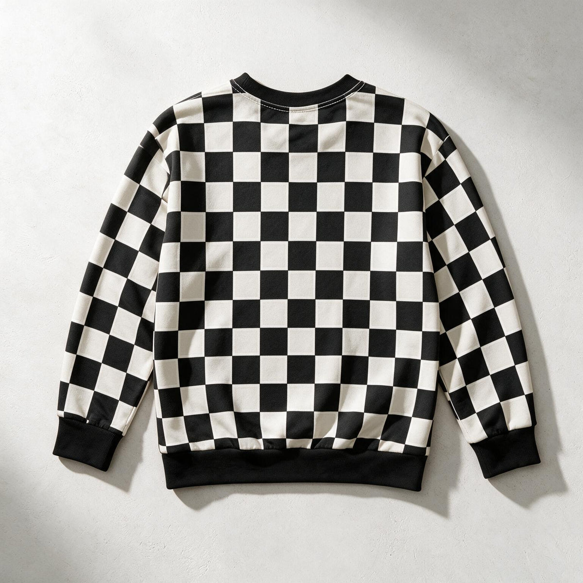 A black and white checkered long-sleeve sweatshirt shown from the back, laid flat on a light gray textured background.
