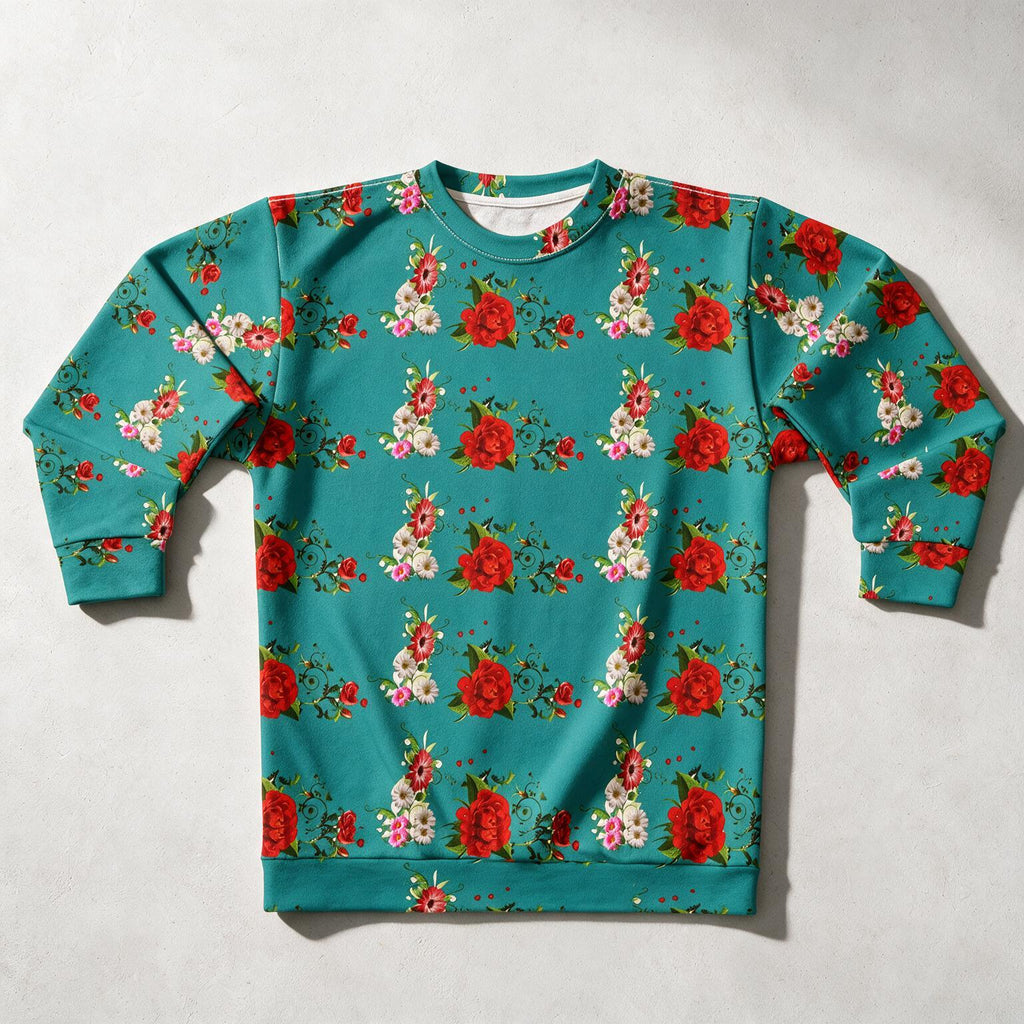 A teal crewneck sweatshirt with an all-over floral print featuring red roses, white blossoms, and green leaves, laid flat on a light gray background.