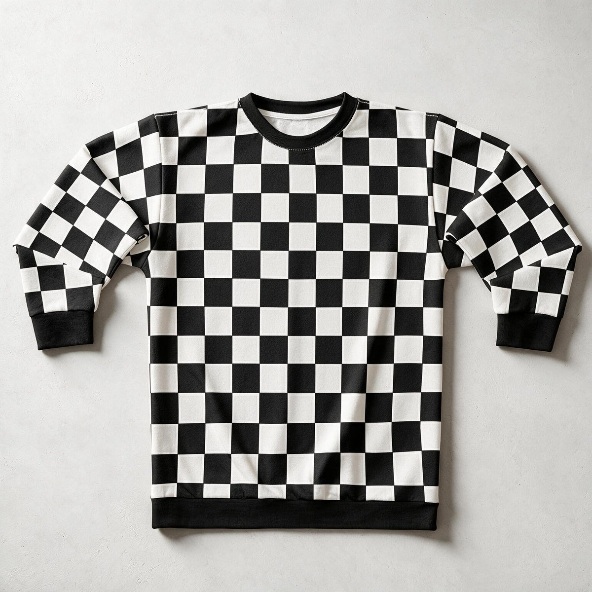 A long-sleeve crewneck sweatshirt featuring a bold black and white checkerboard pattern, laid flat on a light gray background.