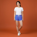 Woman wearing a white t-shirt and blue shorts on an orange background