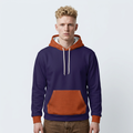A man wearing a color-blocked pullover hoodie with a navy blue body, rust orange hood lining and cuffs, and a textured rust orange kangaroo pocket, set against a plain light gray background.