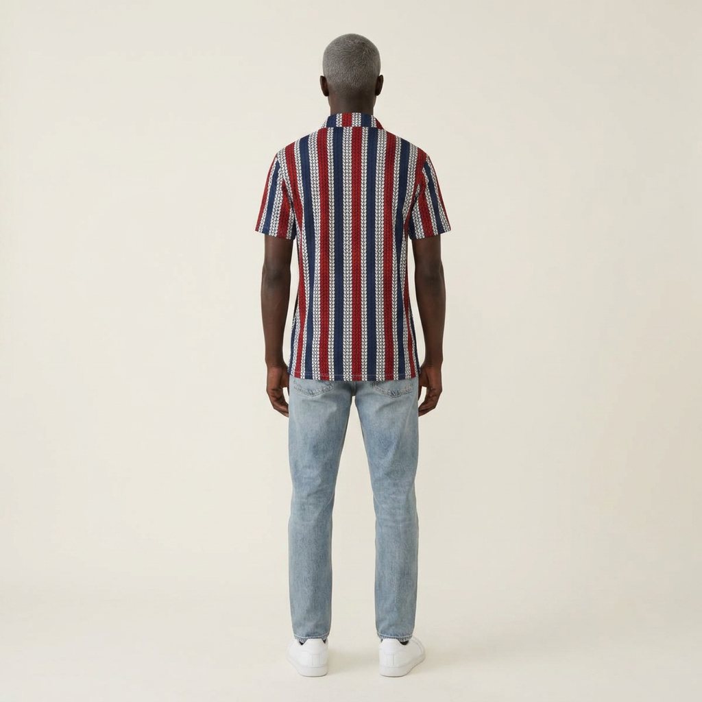 A man viewed from behind wearing a short-sleeve button-up shirt with vertical red, white, and navy stripes, paired with light blue jeans and white sneakers, against a plain off-white studio background.