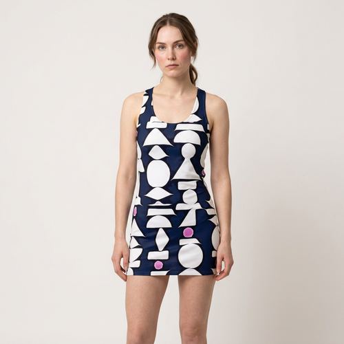 A woman modeling a sleeveless mini dress with a navy blue and white geometric pattern, featuring pink circular accents, against a plain light gray background.
