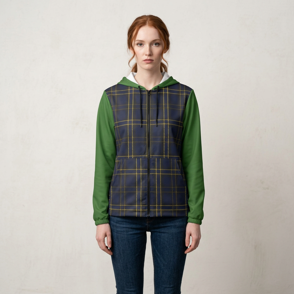 A woman stands against a light textured wall wearing a hooded zip-front jacket with green sleeves and a navy plaid body, paired with dark blue jeans.