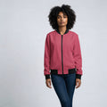 Person wearing a pink bomber jacket with black accents on a plain background